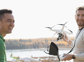 Two people holding drones whilst smiling